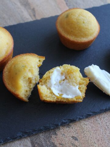 overhead view of a cornbread muffin cut in half and spread with butter