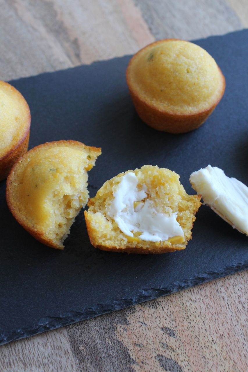 overhead view of a cornbread muffin cut in half and spread with butter
