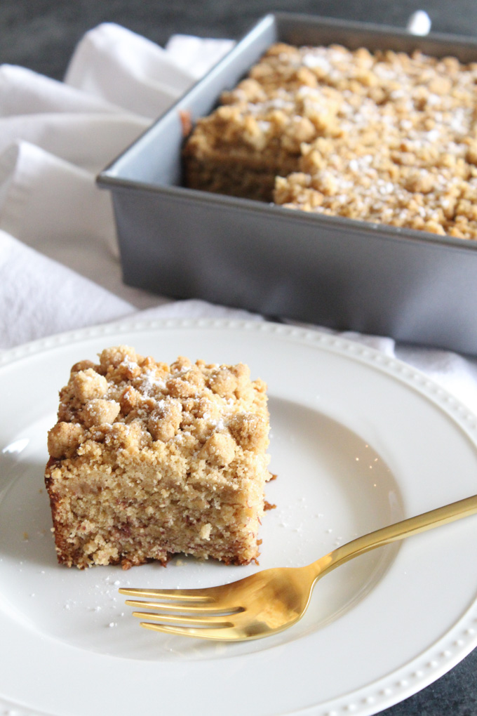 angled view of a slice of crumb cake on a white plate