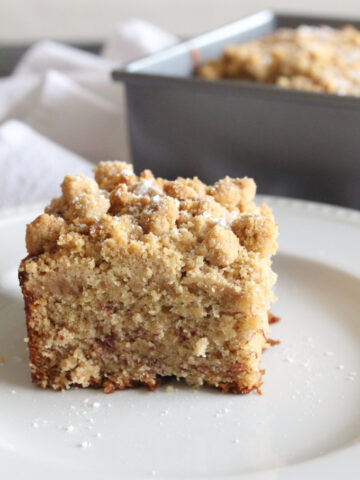 side view of a slice of crumb cake on a white plate