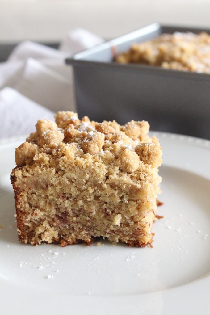 side view of a slice of crumb cake on a white plate