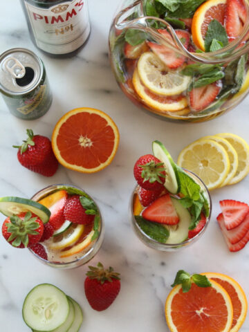 overhead view of cocktails garnished with fresh fruit on a marble surface