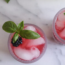 overhead view of blackberry lemonade in a glass garnished with a fresh basil sprig