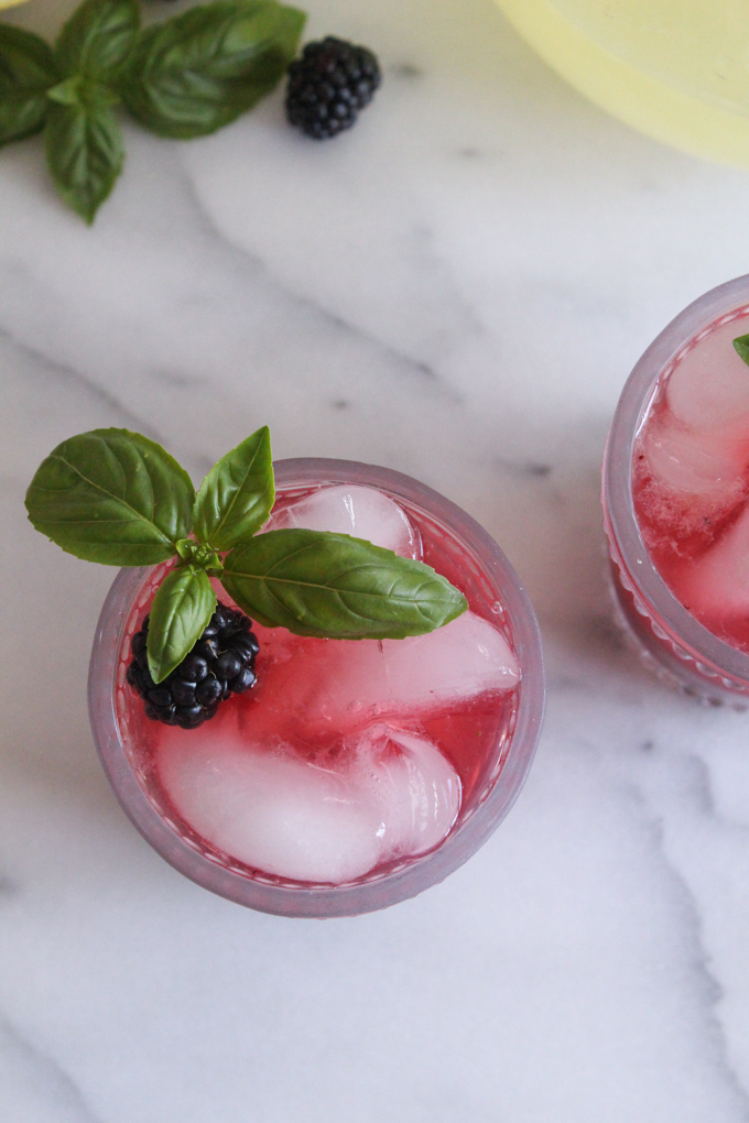 overhead view of blackberry lemonade in a glass garnished with a fresh basil sprig