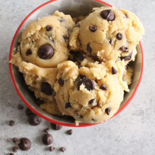 Overhead view of cookie dough with chocolate chips in a bowl on a gray surface.
