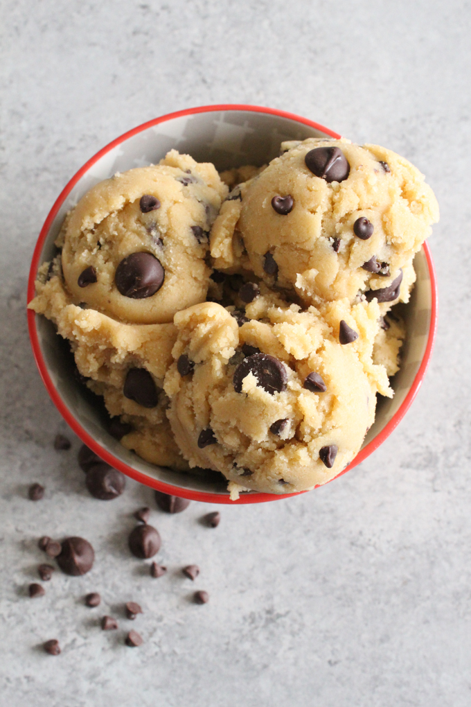 Overhead view of cookie dough with chocolate chips in a bowl on a gray surface.