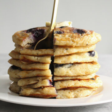 Stack of pancakes on a plate with a fork.