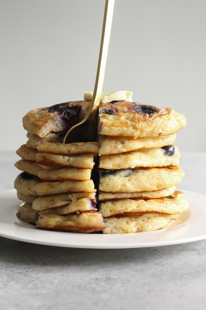 Stack of pancakes on a plate with a fork.