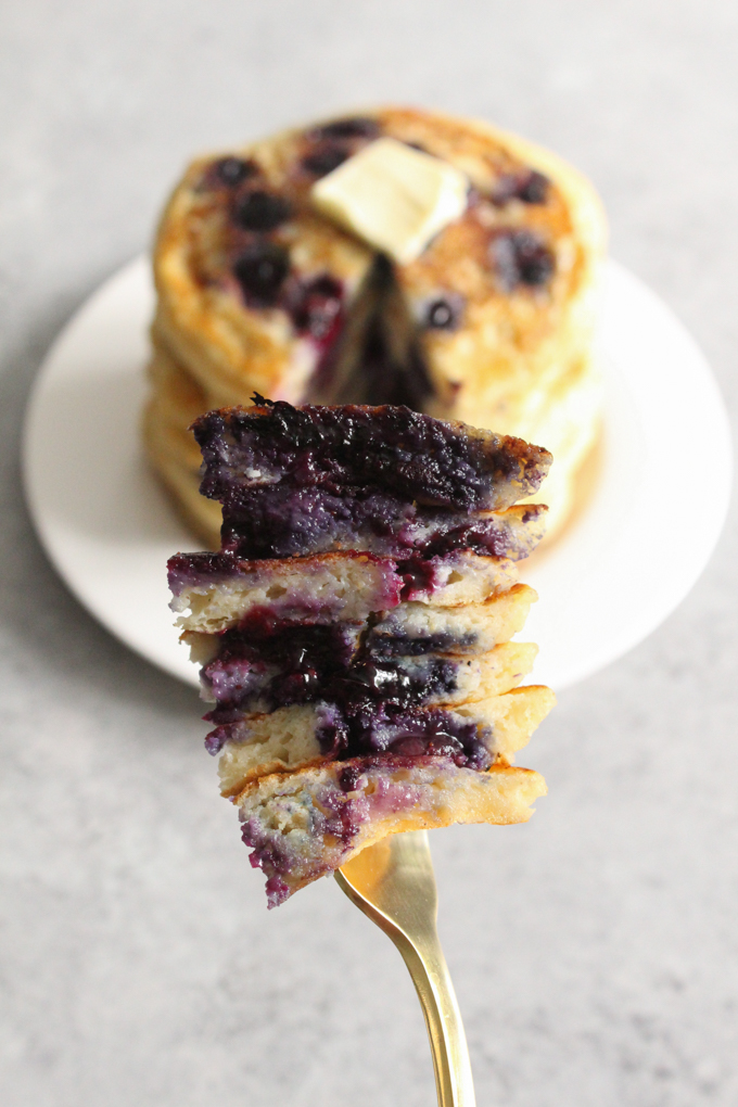 Slices of blueberry pancake stacked on a fork.