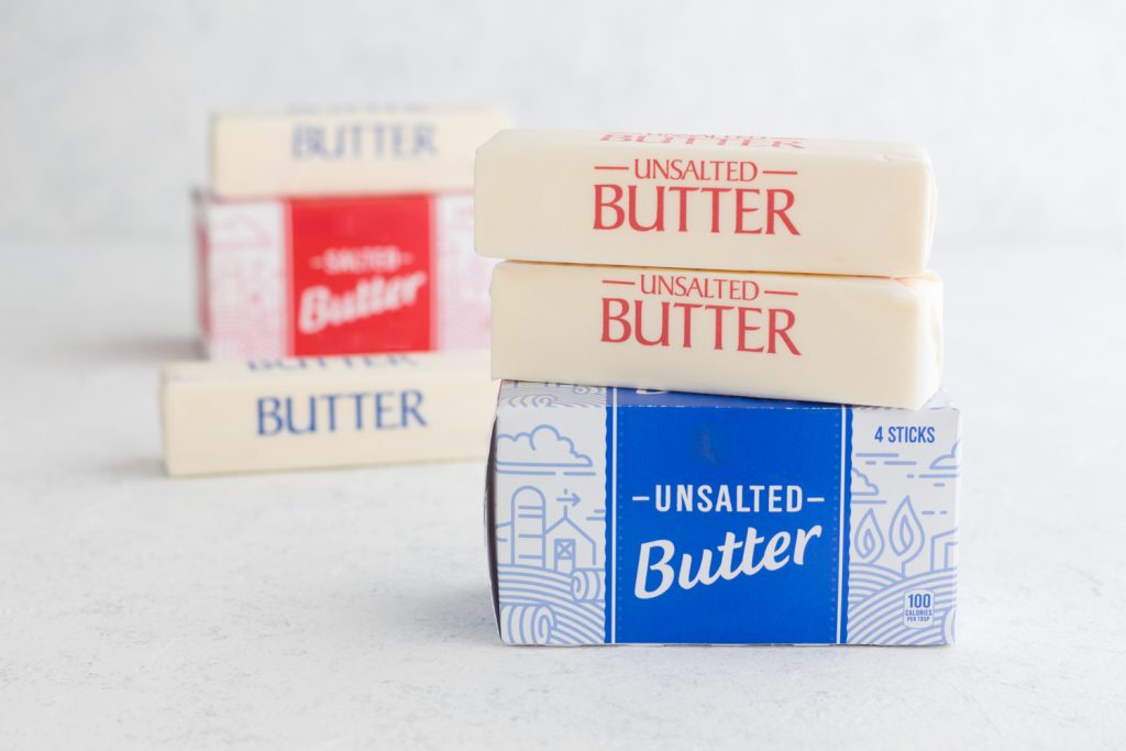 sticks of butter and butter boxes stacked on a white surface