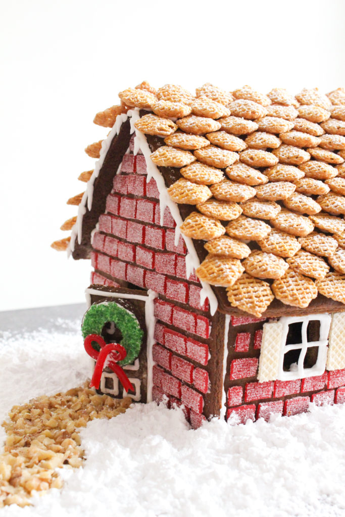 Side view of a gingerbread house with red "brick" walls and a cereal roof.