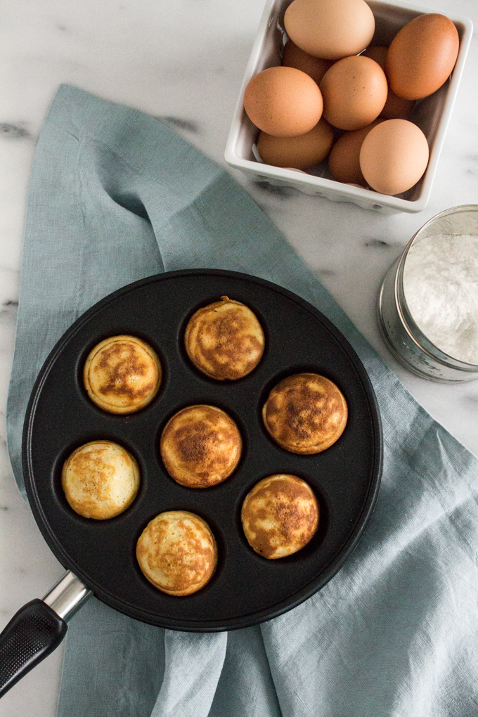 overhead view of Nutella-stuffed ebelskivers (Danish pancakes) dusted with confectioners' sugar on a marble surface