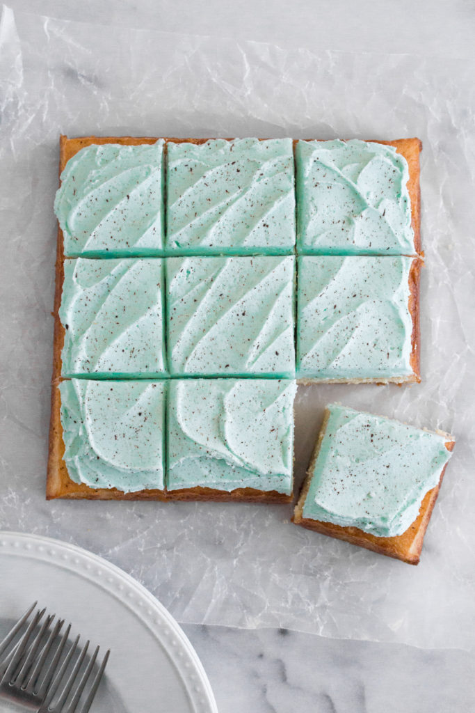 Overhead view of a square cake sliced into 9 squares on a marble surface.