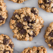 overhead view of oatmeal dark chocolate chunk breakfast cookies scattered on a marble surface