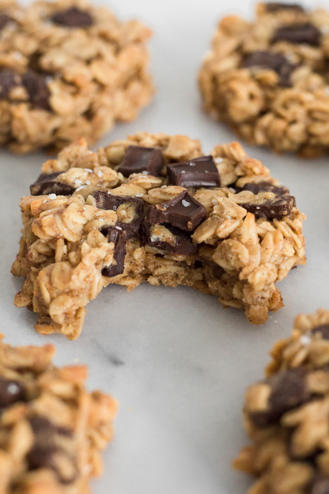 close-up side view of oatmeal dark chocolate chunk breakfast cookies with a bite missing on a marble surface