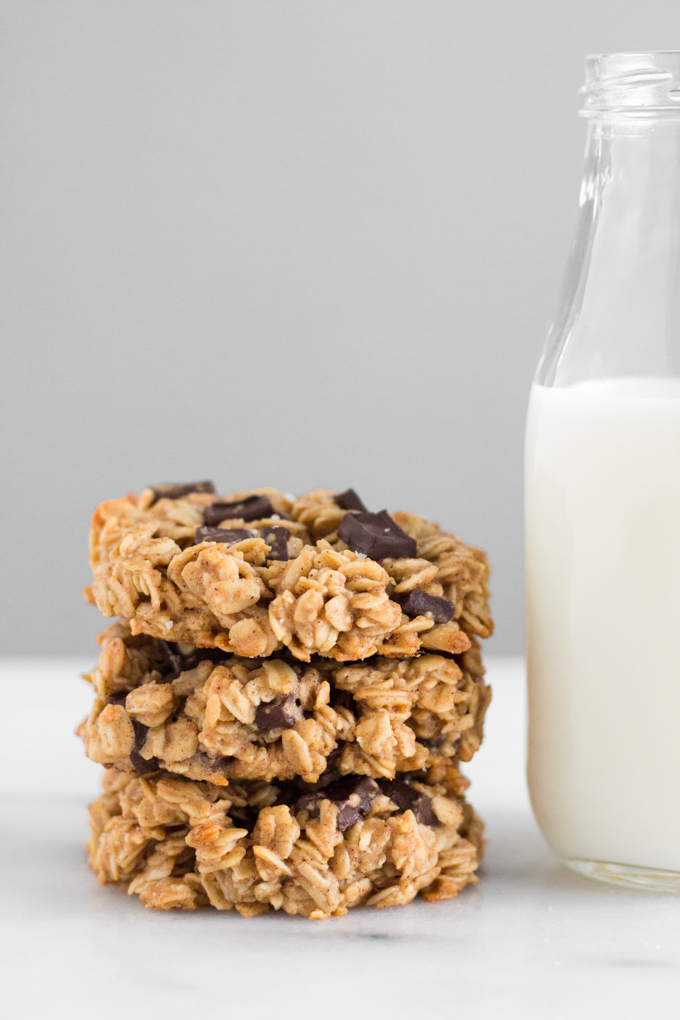 stacked oatmeal dark chocolate chunk breakfast cookies with a glass of milk on a marble surface