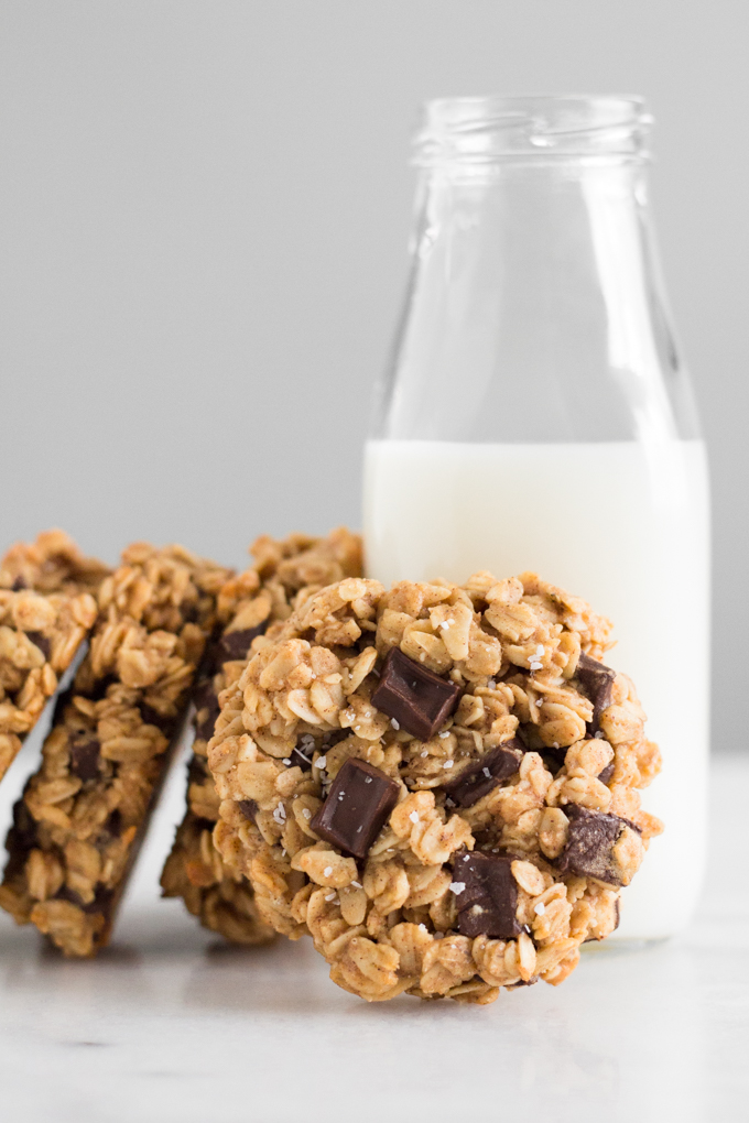 stacked oatmeal dark chocolate chunk breakfast cookies with a glass of milk on a marble surface
