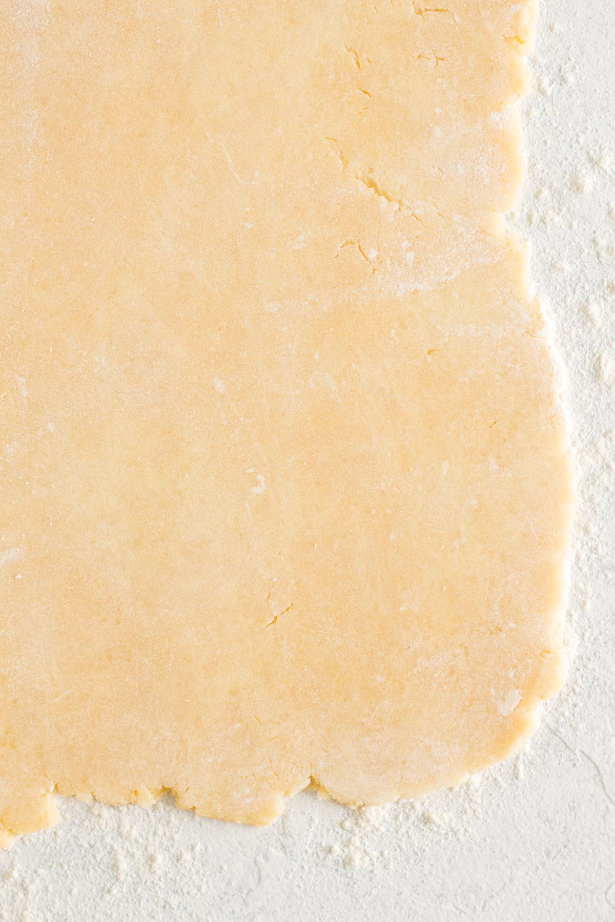 Rolled out pie crust dough on a floured white surface.