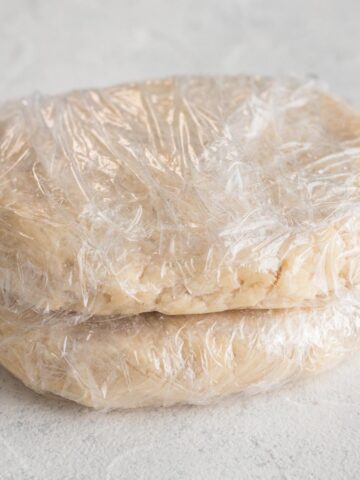 Flattened discs of pie crust dough on a white surface.