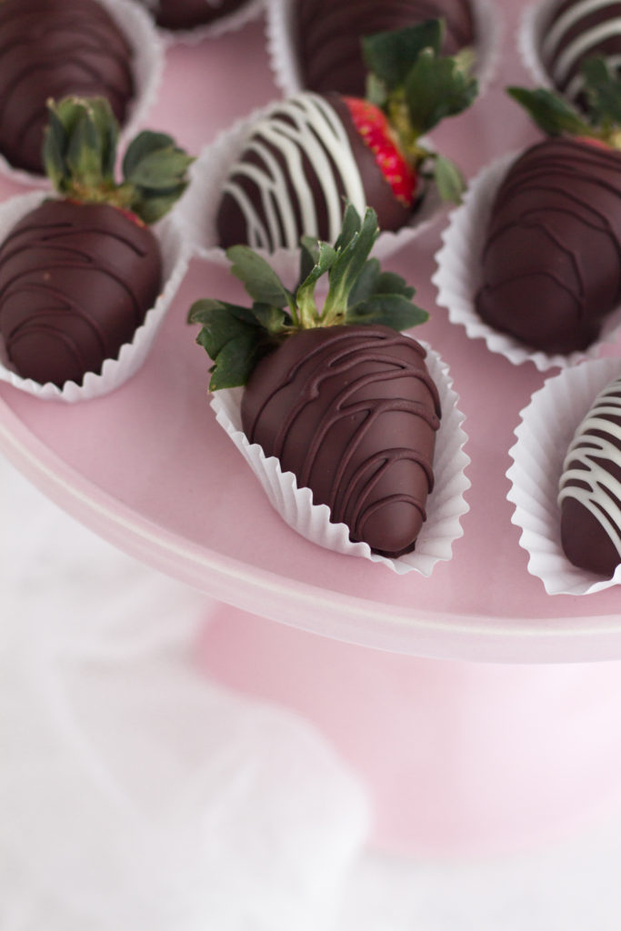 Overhead view of chocolate covered strawberries on a pink cake stand.