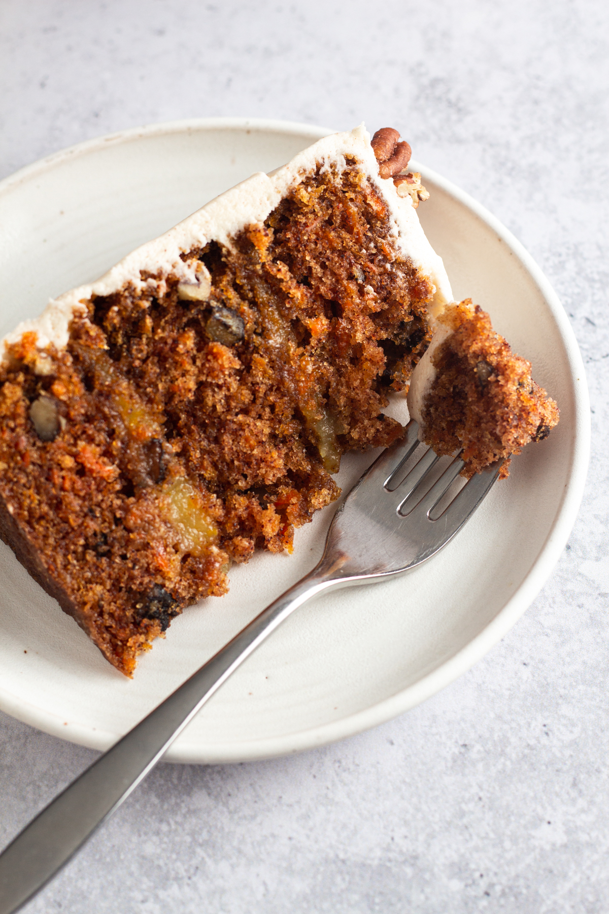 overhead view of a slice of carrot cake on a white plate with a fork