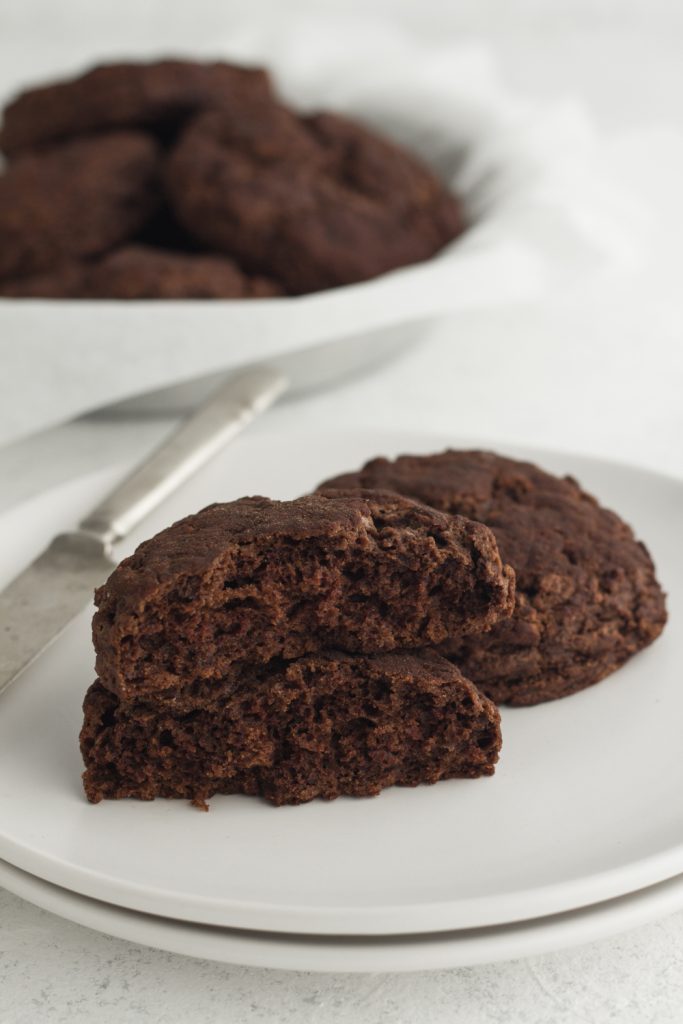 angled view of sliced chocolate buttermilk biscuits stacked on white plates on a white background