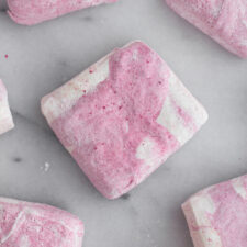 overhead view of homemade raspberry swirl marshmallows on a marble surface