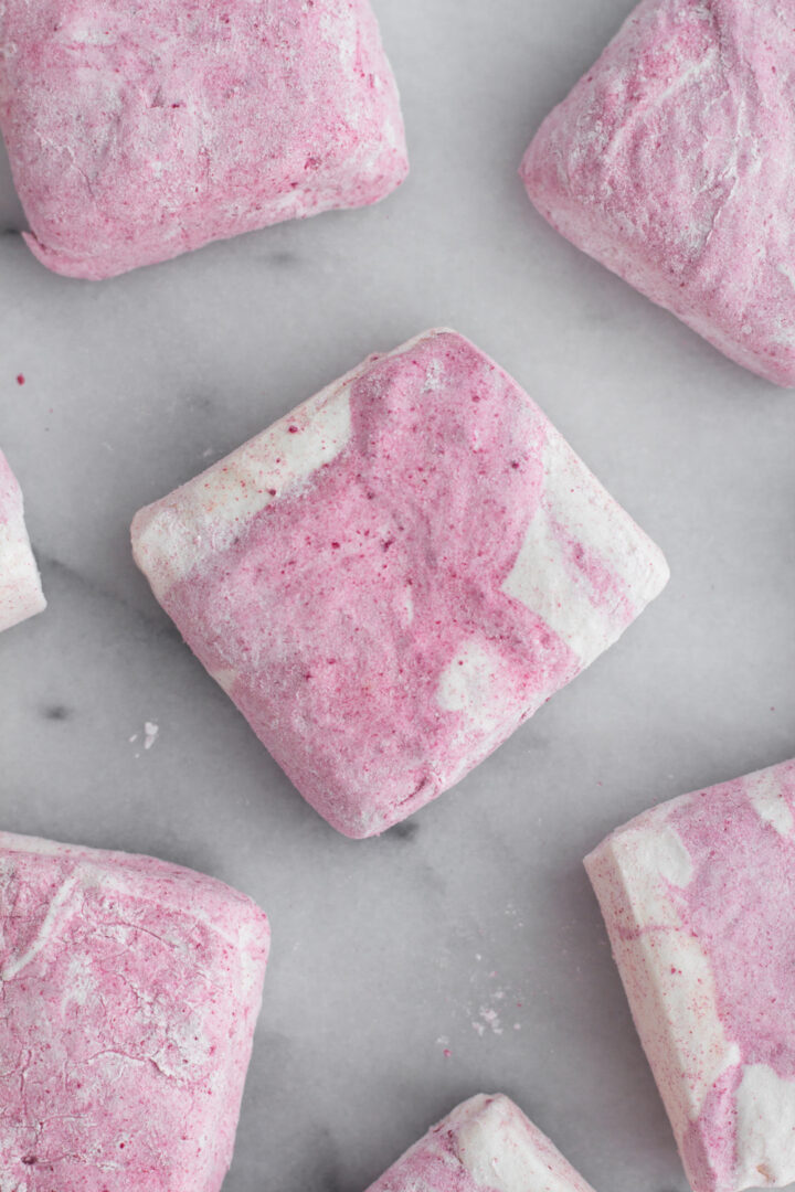 overhead view of homemade raspberry swirl marshmallows on a marble surface