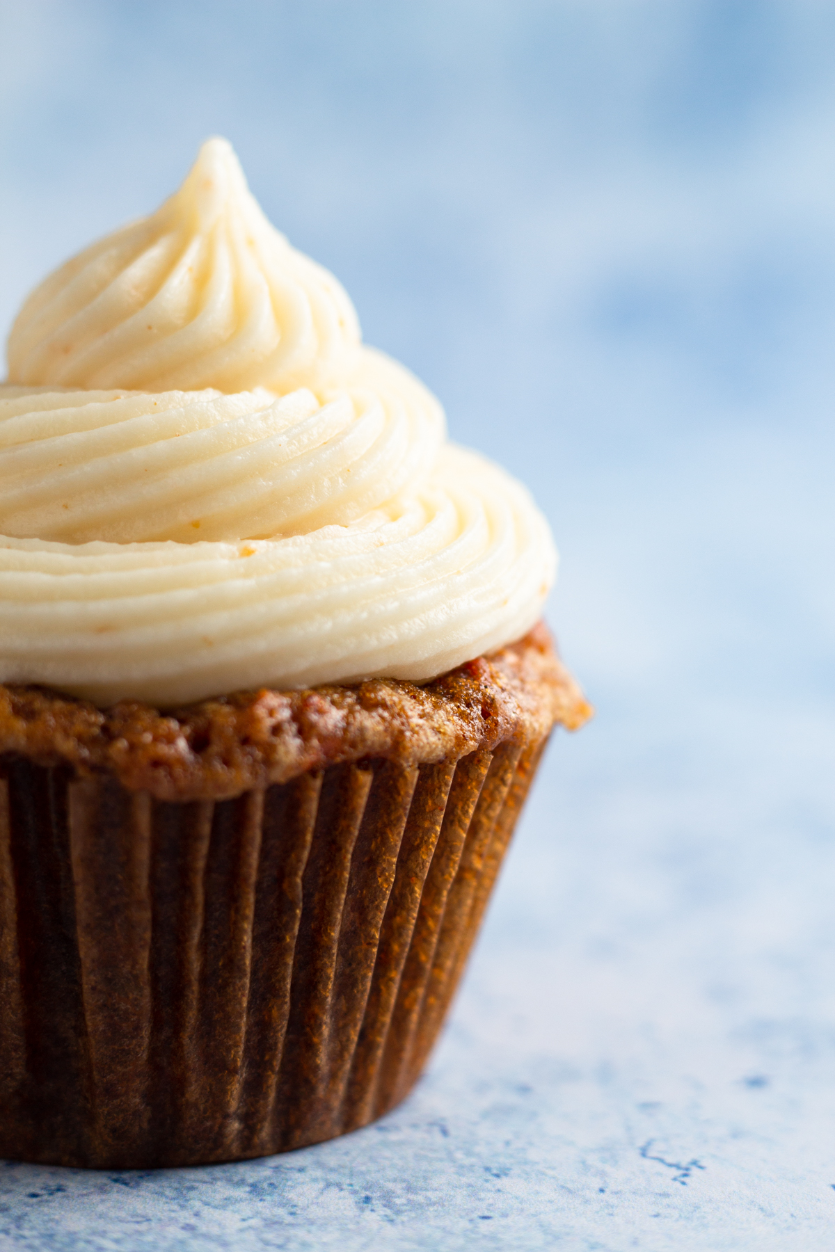 close up side view of a cupcake topped with a swirl of frosting