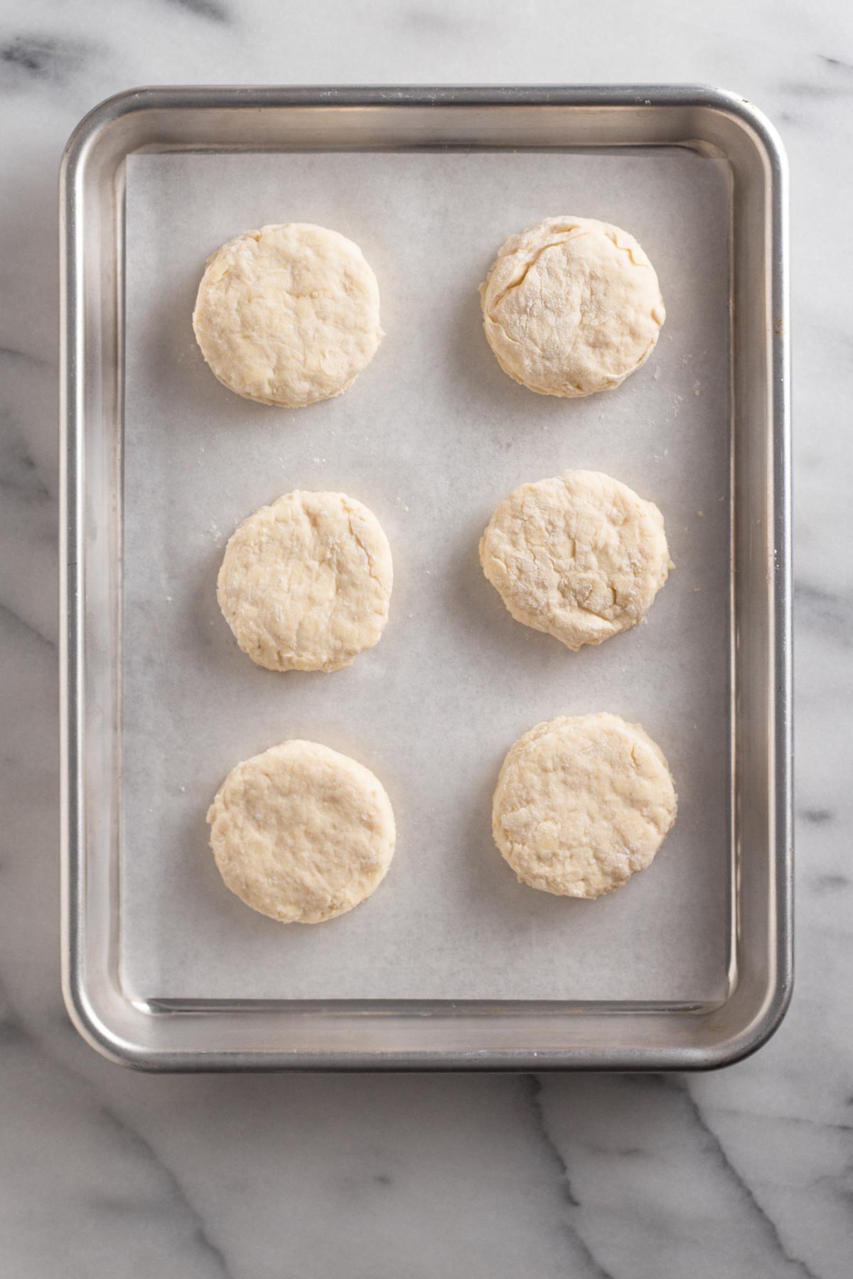 overhead view of circles of biscuit dough on a baking sheet with parchment paper