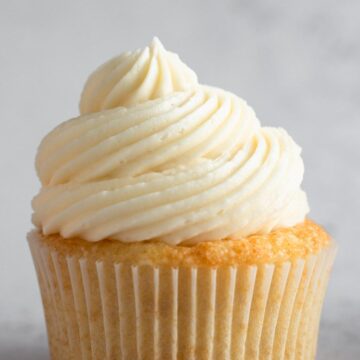 a swirl of vanilla frosting on top of a vanilla cupcake