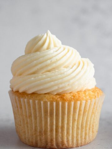 a swirl of vanilla frosting on top of a vanilla cupcake