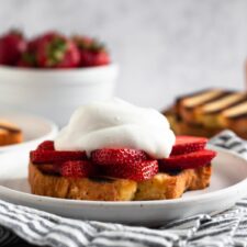 side view of a slice of pound cake topped with sliced strawberries and whipped cream