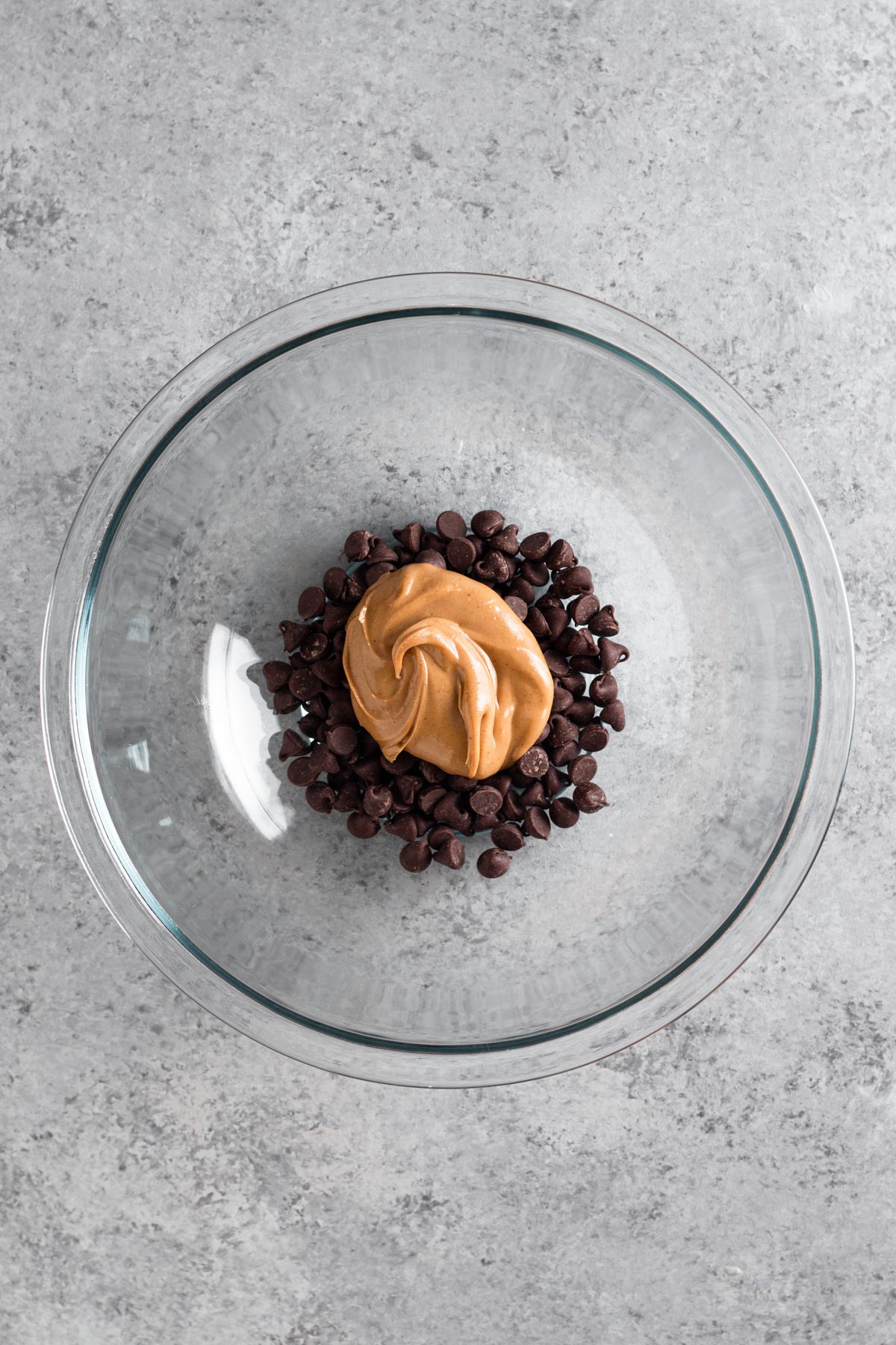 overhead view of chocolate chips and peanut butter in a glass bowl