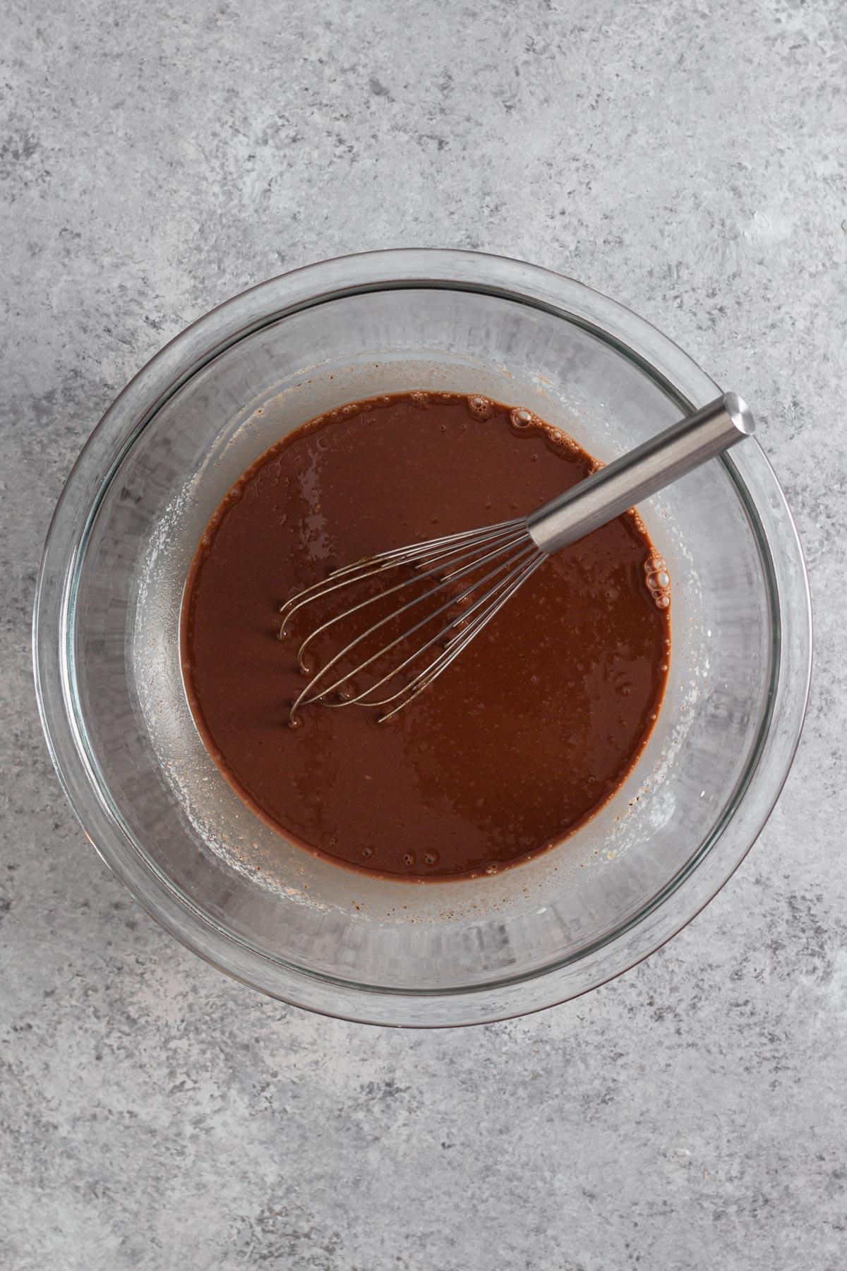 overhead view of chocolate mixture in a glass bowl with a metal whisk