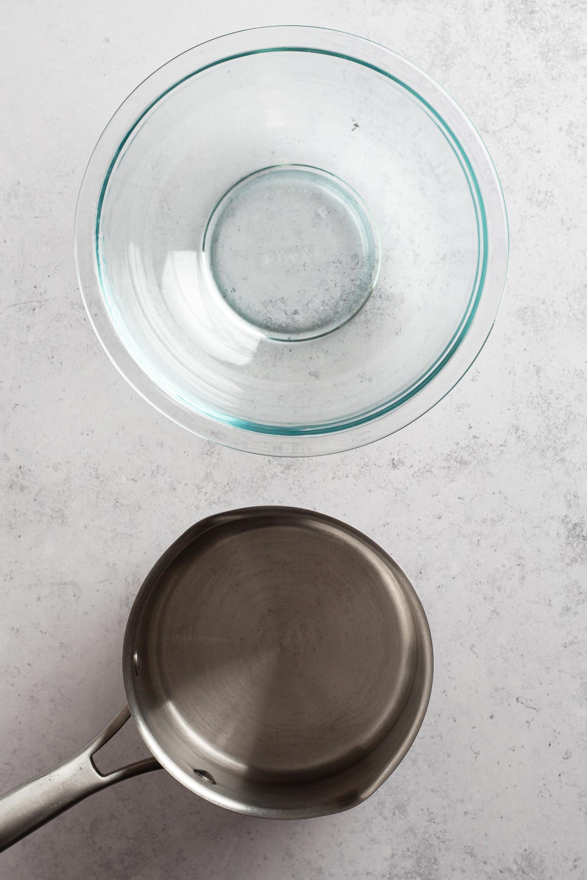 saucepan and glass bowl on a gray surface