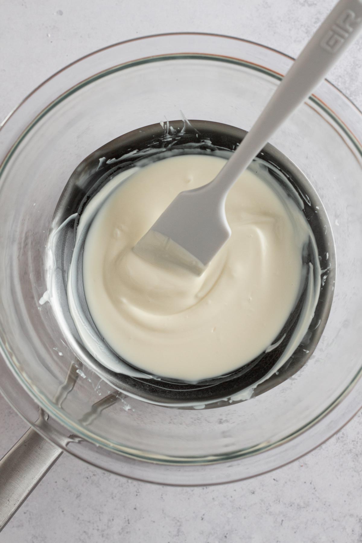 melted white chocolate in a double boiler with a white spatula