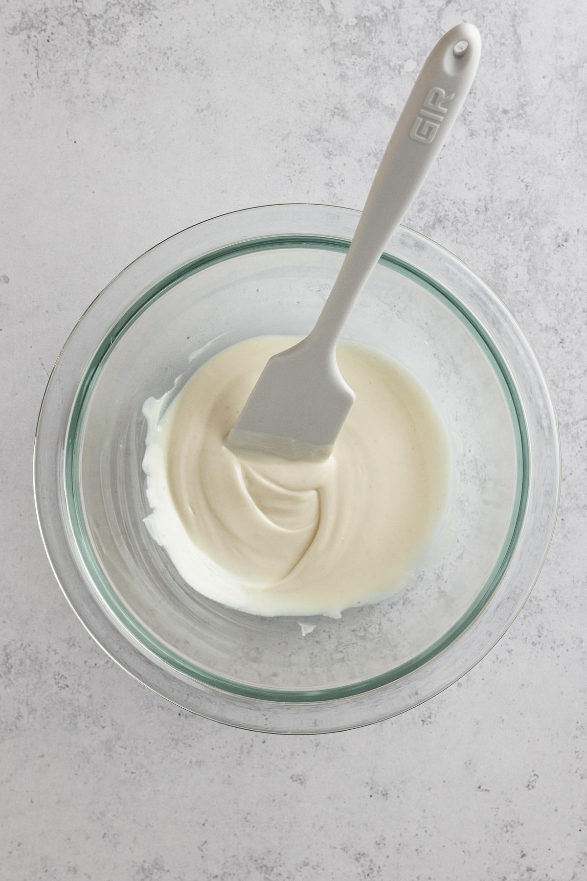 melted white chocolate in a glass bowl with a white spatula