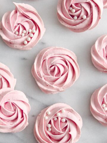 blush pink meringue cookies on a marble surface