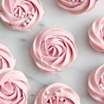 Pink meringue cookies on a marble surface.