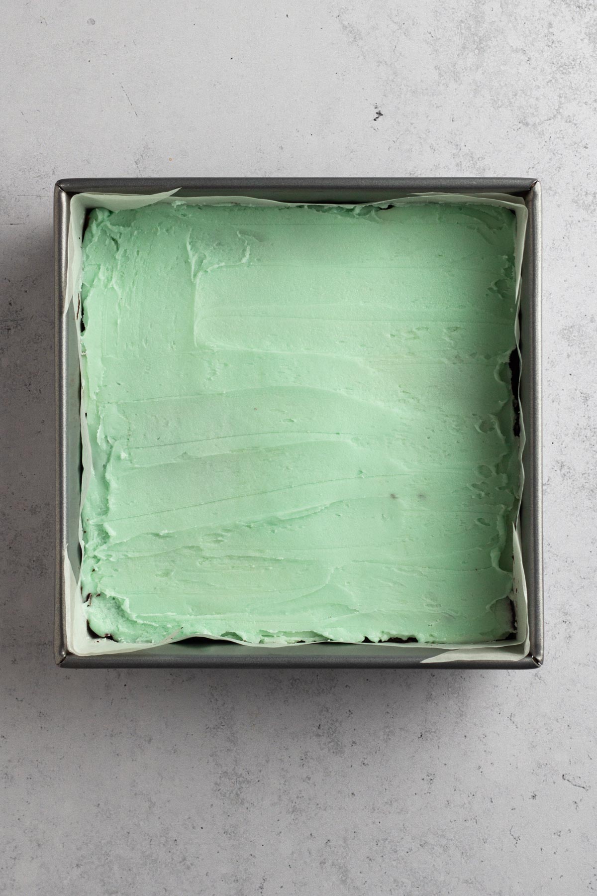 overhead view of creme de menthe frosting spread onto brownies in a metal pan