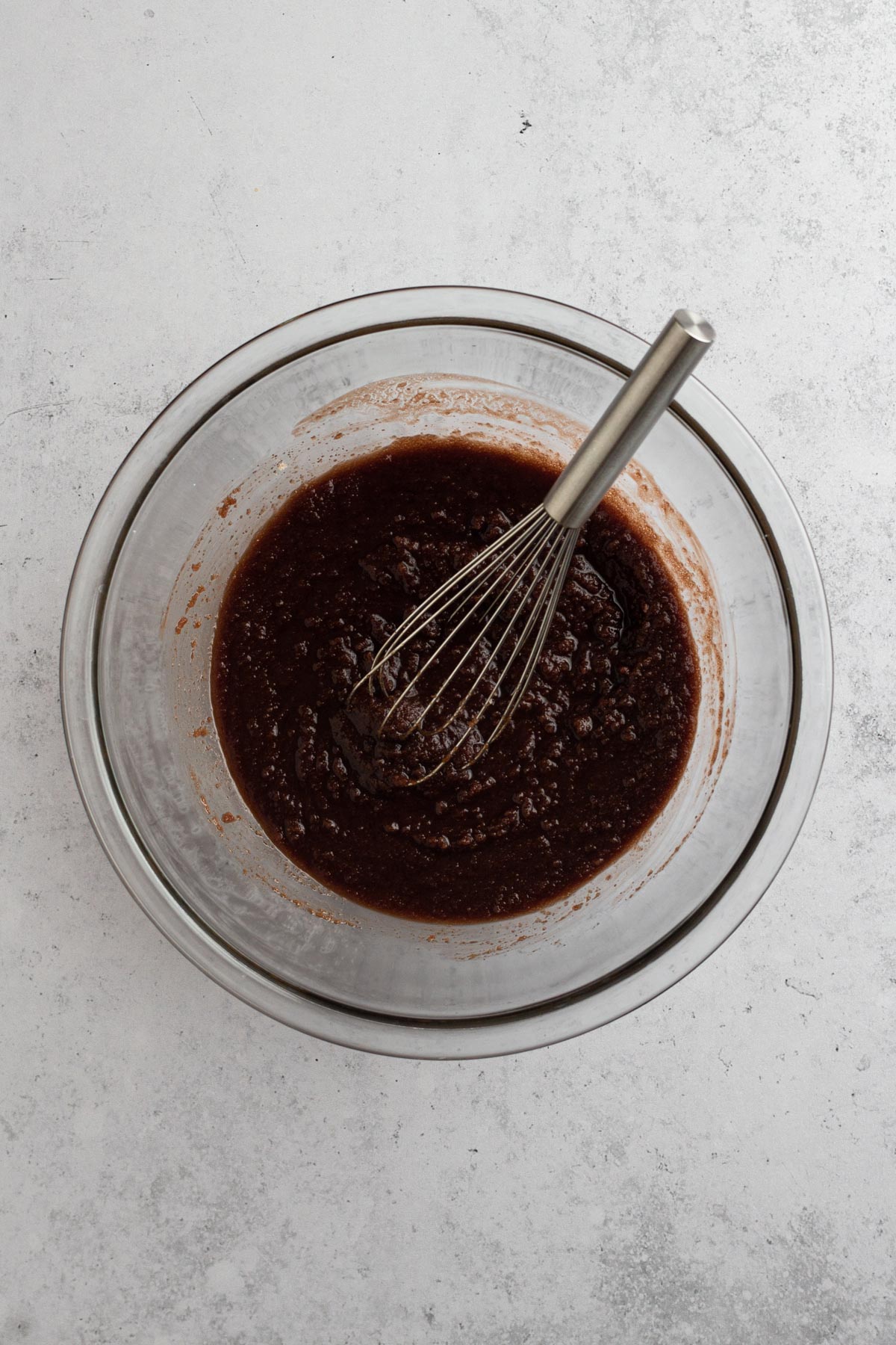 overhead view of melted chocolate and sugar whisked together in a glass bowl