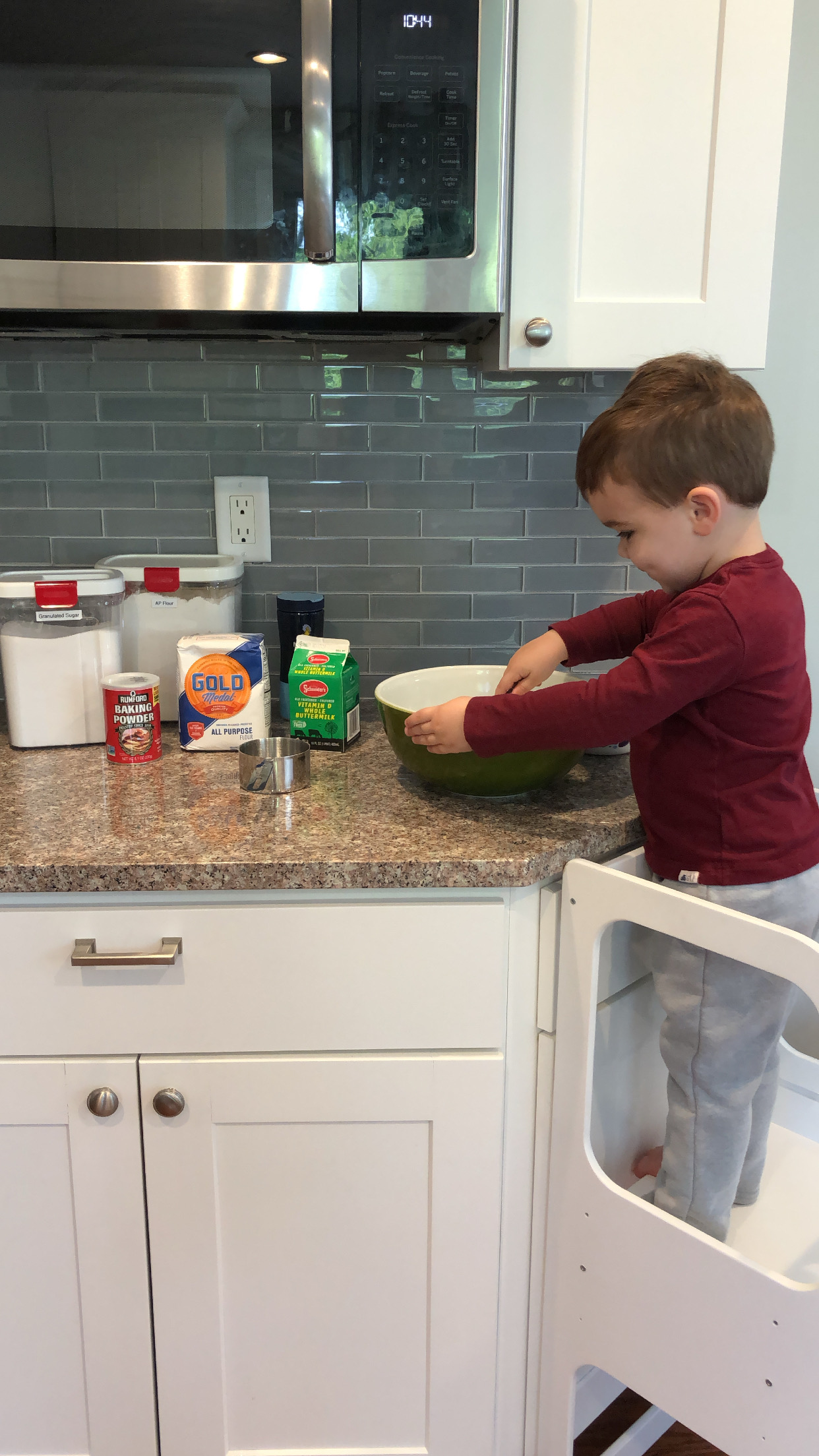 Toddler whisking ingredients together in a mixing bowl.