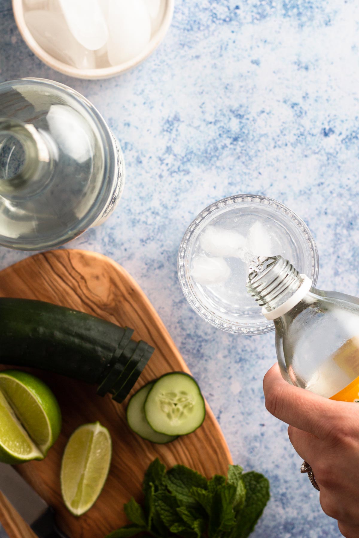 Pouring tonic into a rocks glass with gin and ice.