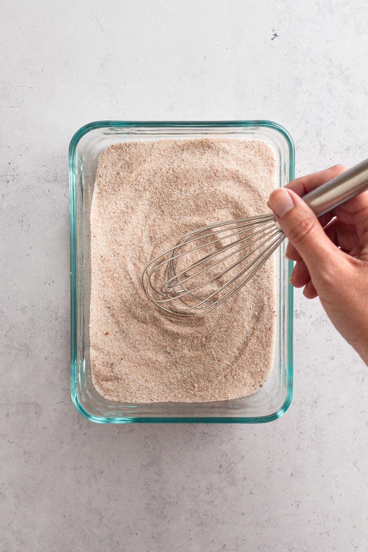 Hand whisking together spiced sugar topping in a glass dish.