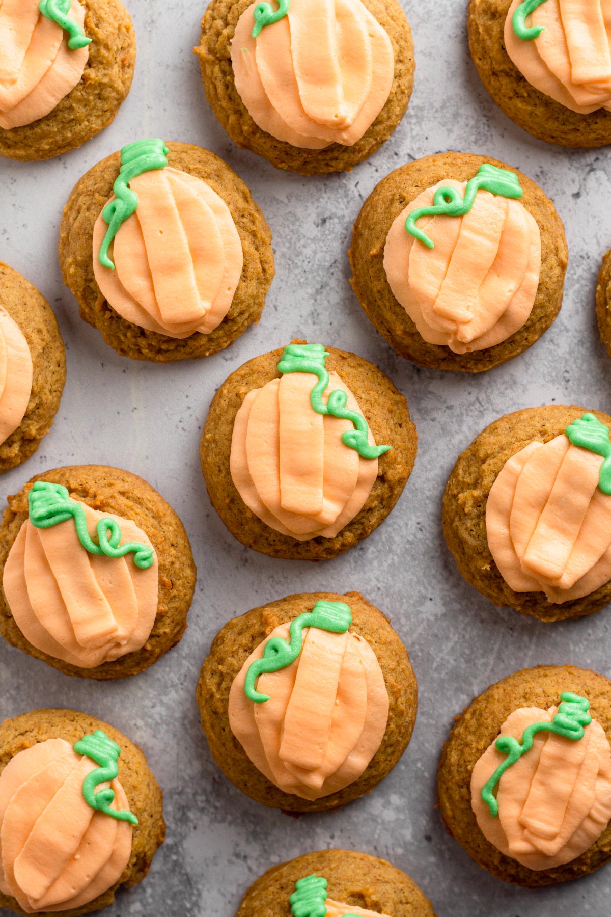 Decorated pumpkin cookies on a gray surface.