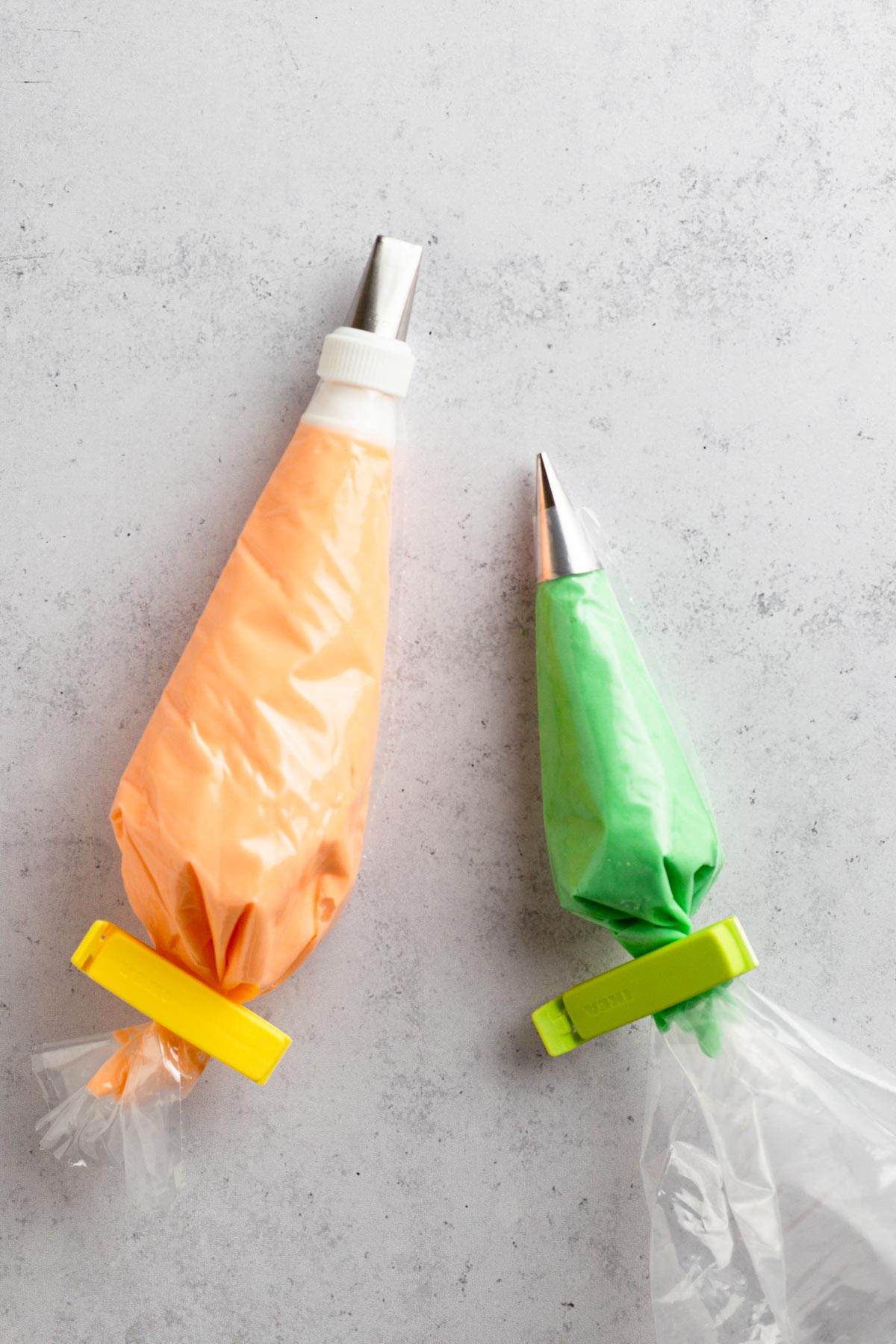 Orange and green frosting in pastry bags with piping tips.