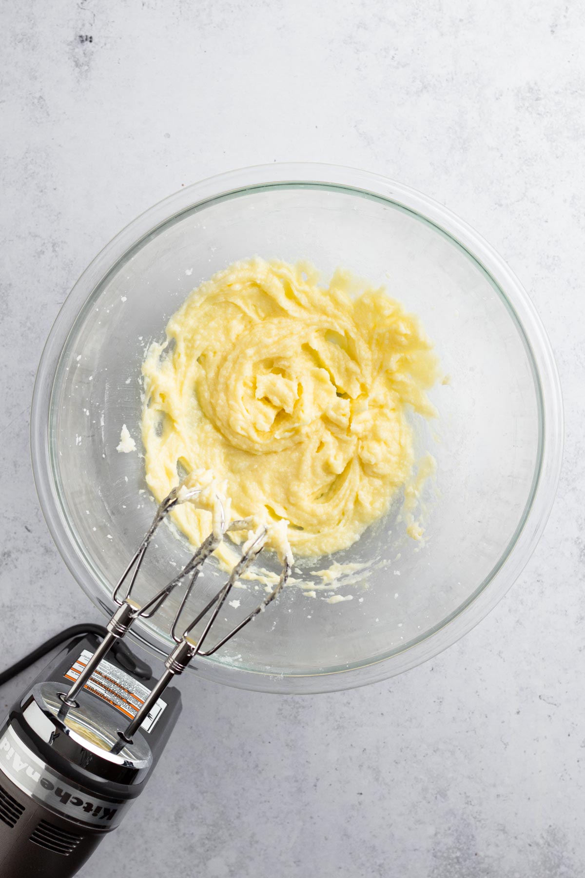 Butter, sugar, and eggs beaten together in a glass bowl.