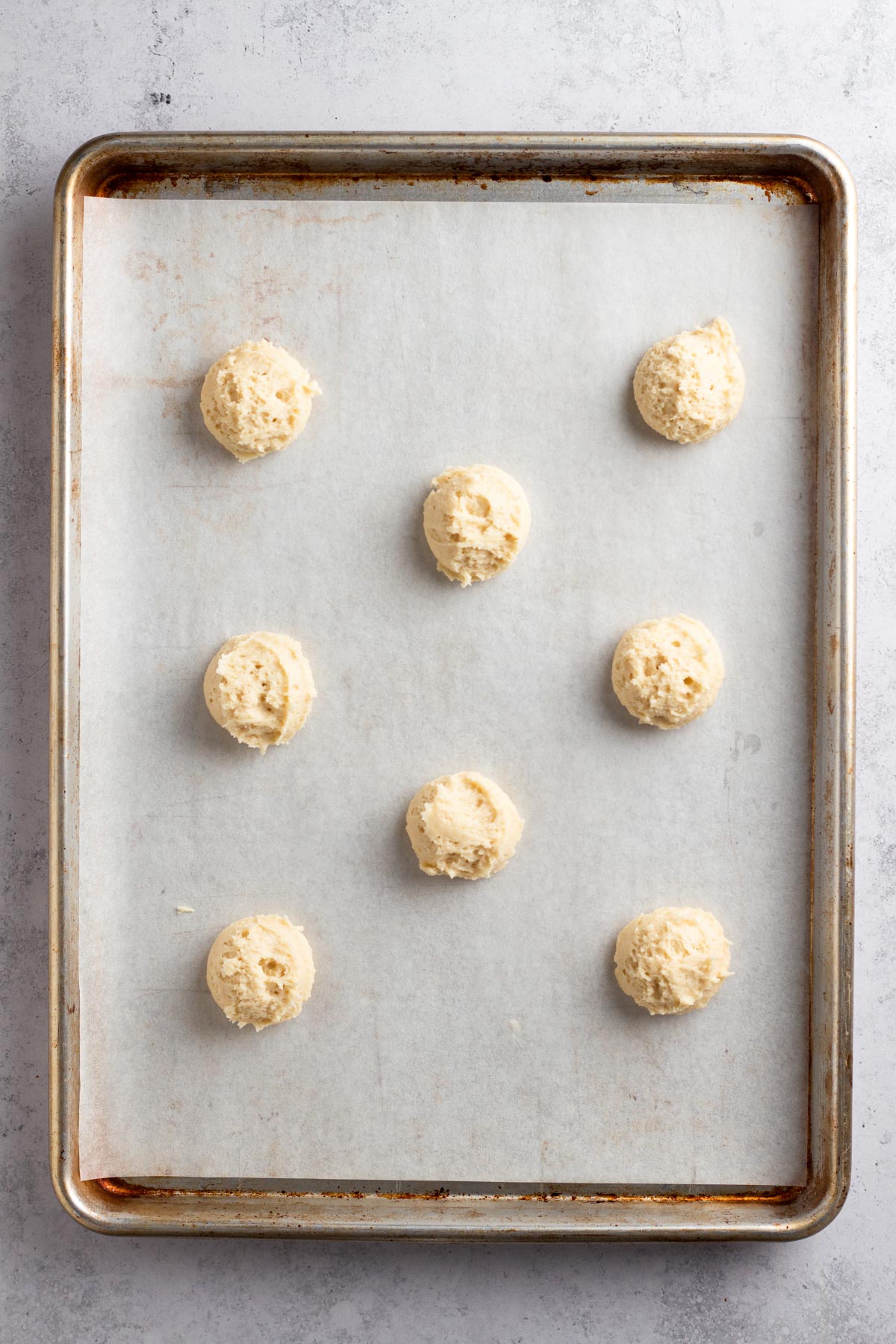 Scoops of cookie dough on a parchment-lined baking sheet.