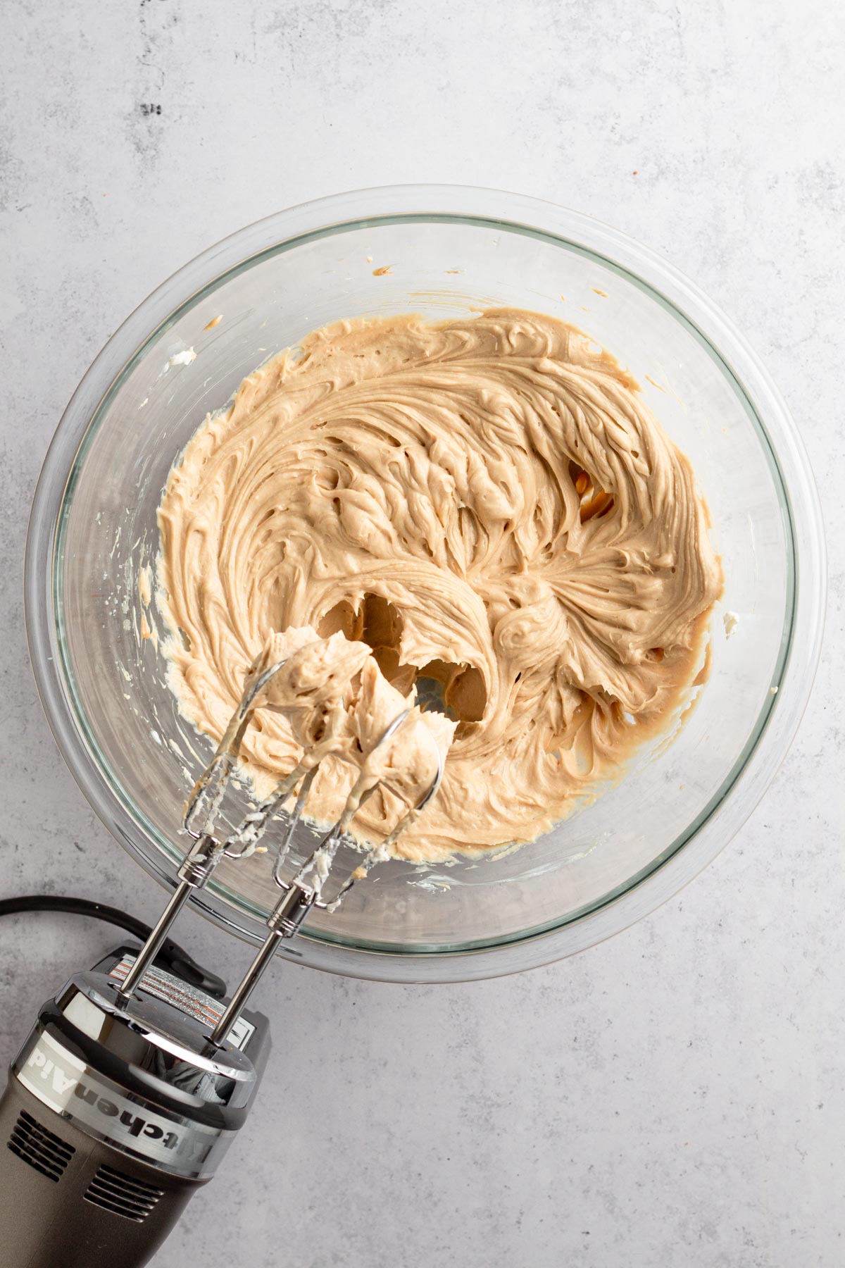 Cream cheese mixture in a glass bowl with hand mixer.